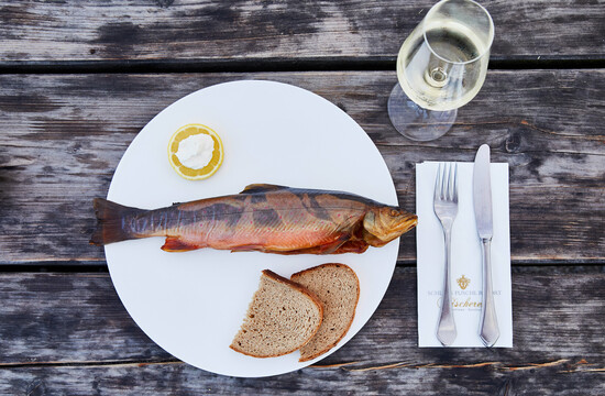 Frisch geräucherter Fuschlsee-Fisch mit Brot und einem Glas Wein.