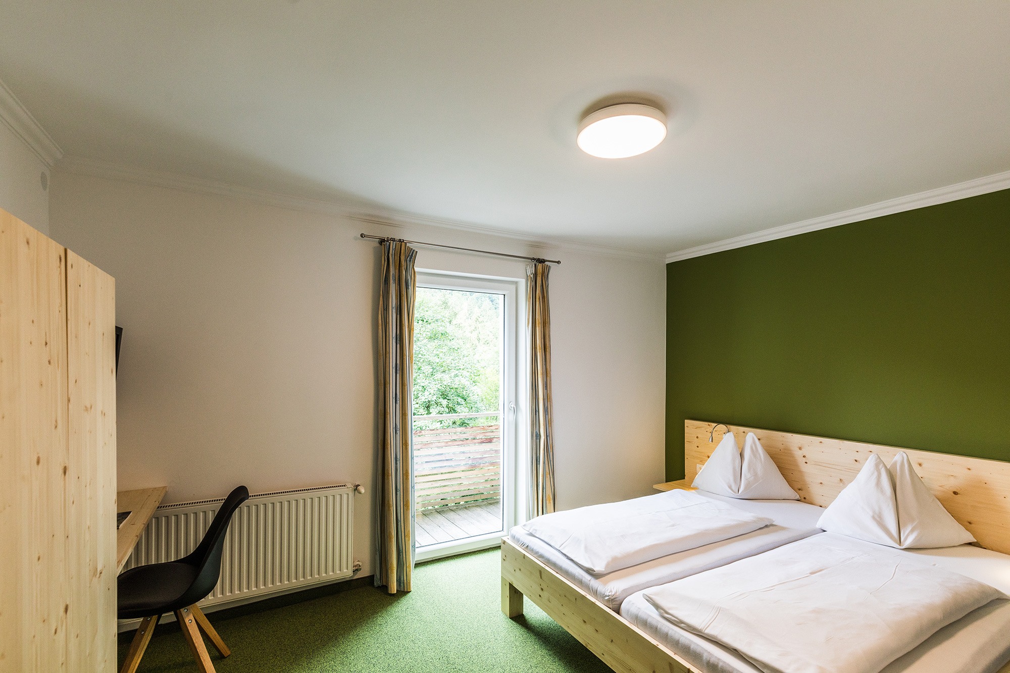 Gemütliches Hotelzimmer mit Doppelbett und Balkon am Salzburgring bei Salzburg.