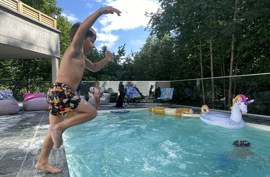 Ein Kind springt beim Familienurlaub im Salzkammergut in den erfrischenden Außenpool