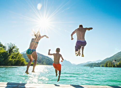 Eine Familie springt im Urlaub beim Fuschlsee in den See