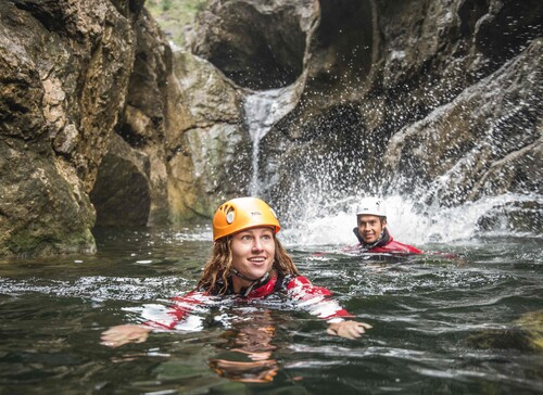 Ein Mann und eine Frau schwimmen beim Canyoning im Aktivurlaub im Salzkammergut durch die Klamm