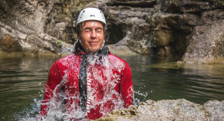 Ein Mann taucht beim Canyoning vom 3* Hotel Obermayr in Salzburg Umgebung aus dem Wasser