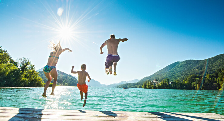 Eine Familie spring beim Badeurlaub im Salzkammergut in den See