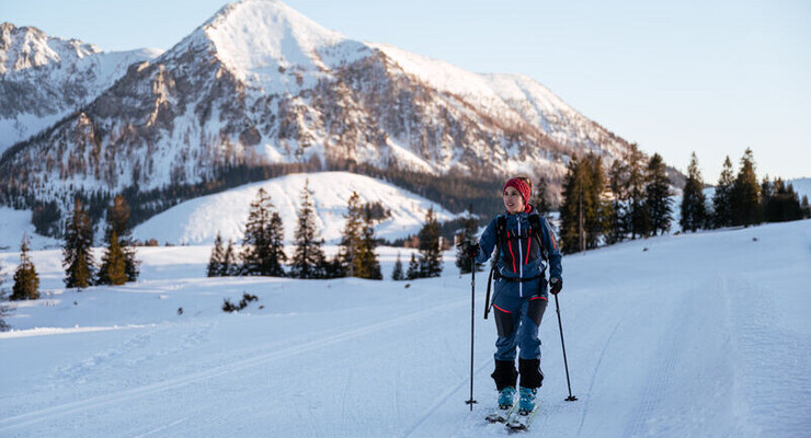 Ein Mann beim Skitouren im Salzkammergut mit seinem Hund